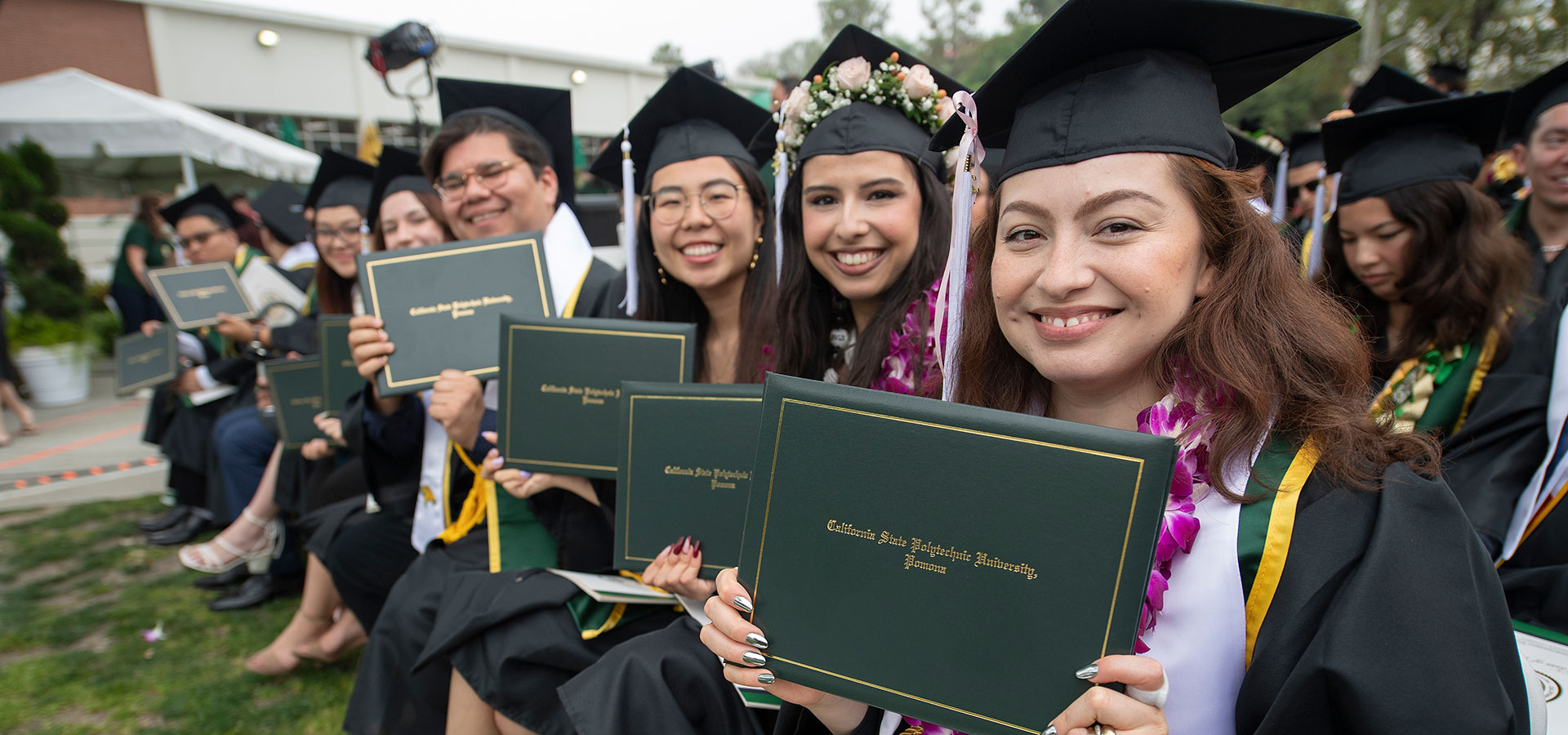 A group of CLASS grads smile while holding their diplomas