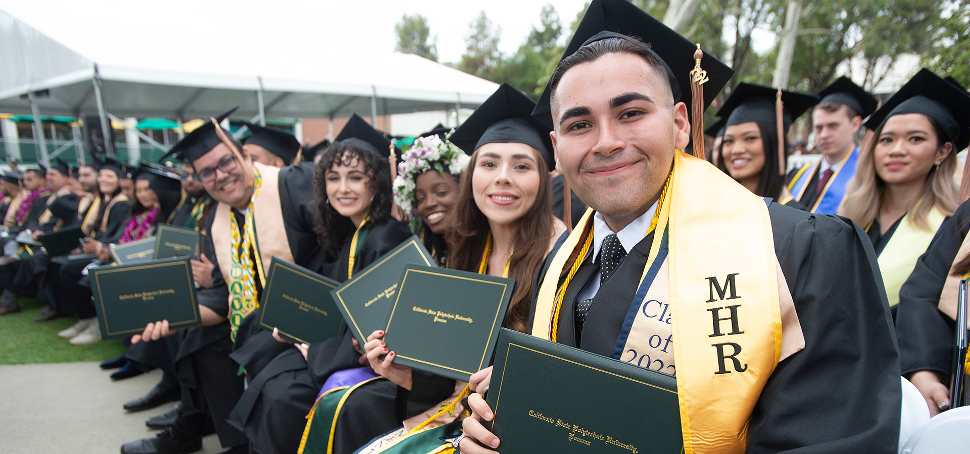 A group of male and female graduates smile during the 2022 College of Business commencement ceremony.