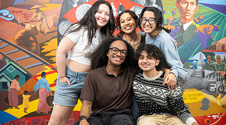 A group of students smile on campus.