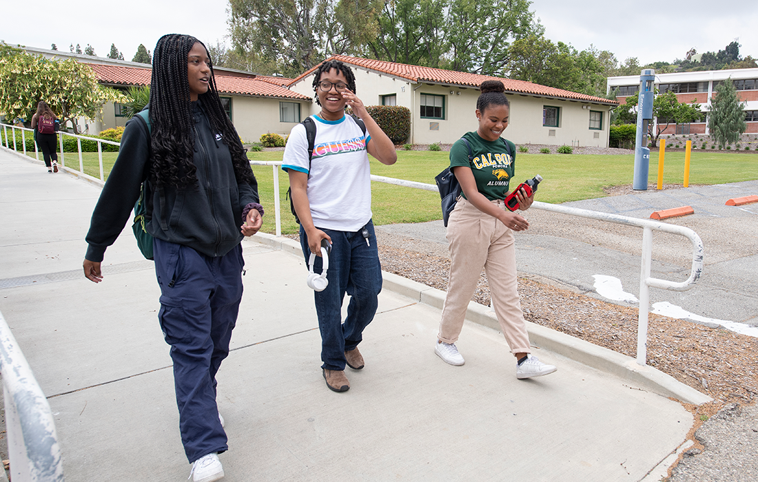 Three students walking across campus while talking.