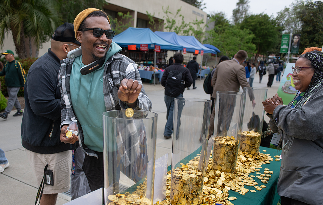 A male student smiles as he drops a coin into a vase.