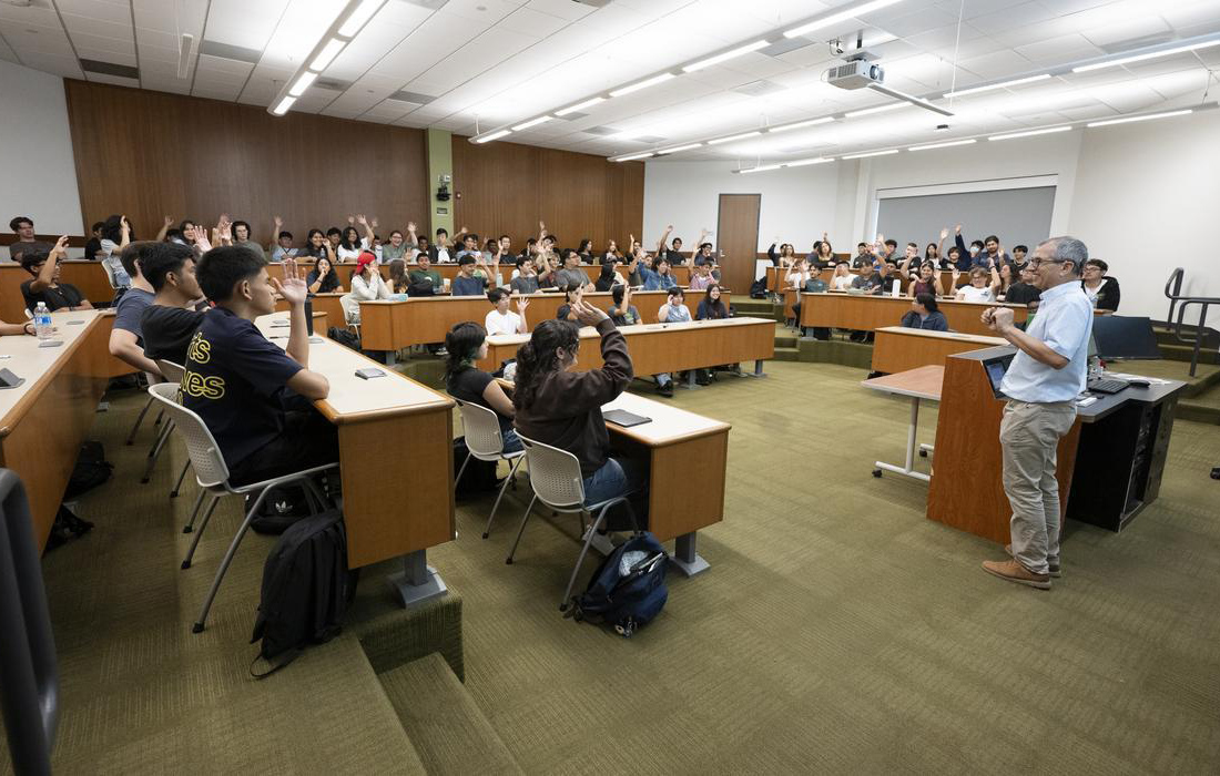 A classroom full of students and a professor teaching at the front