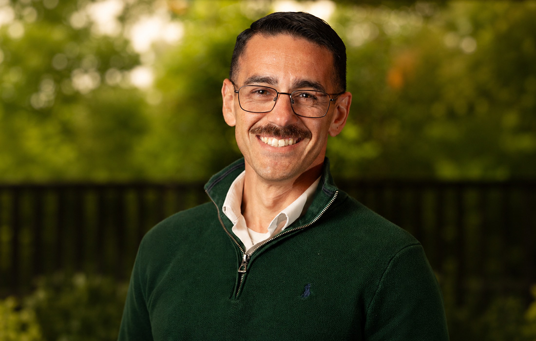 Thomas Sekayan smiling wearing a green sweater.