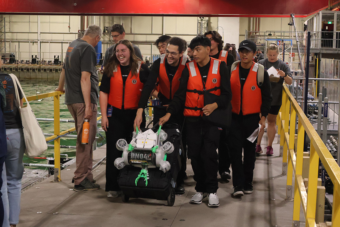 Pomona Subsea Initiative student team from Cal Poly Pomona walk with their remotely operated underwater vechicle (ROV)