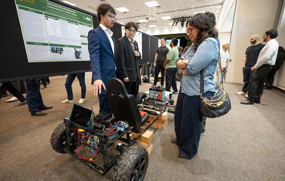 A female attendee stops at the Drive-by-Wire Platform for Autonomous Ground Vehicle presentation.