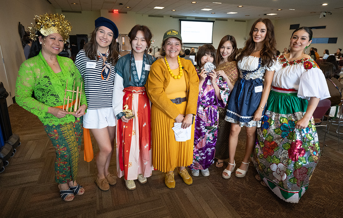 A group of students dressed in international costume designs pose with CPP president Vanya.