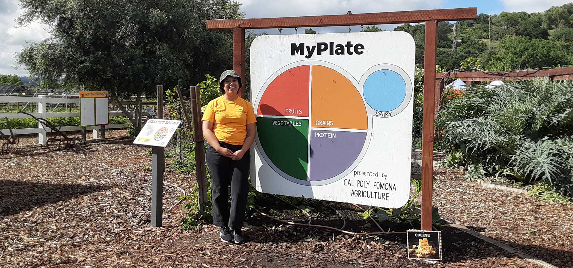 A female student stands in front of a MyPlate display in the Children's Garden at AGRIscapes