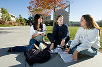Three Cal Poly Pomona Students hanging out by the Engineering Meadow with the CLA Building in the background