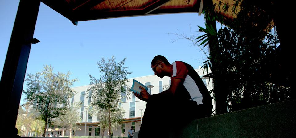student reading a book in front of the CBA buildings