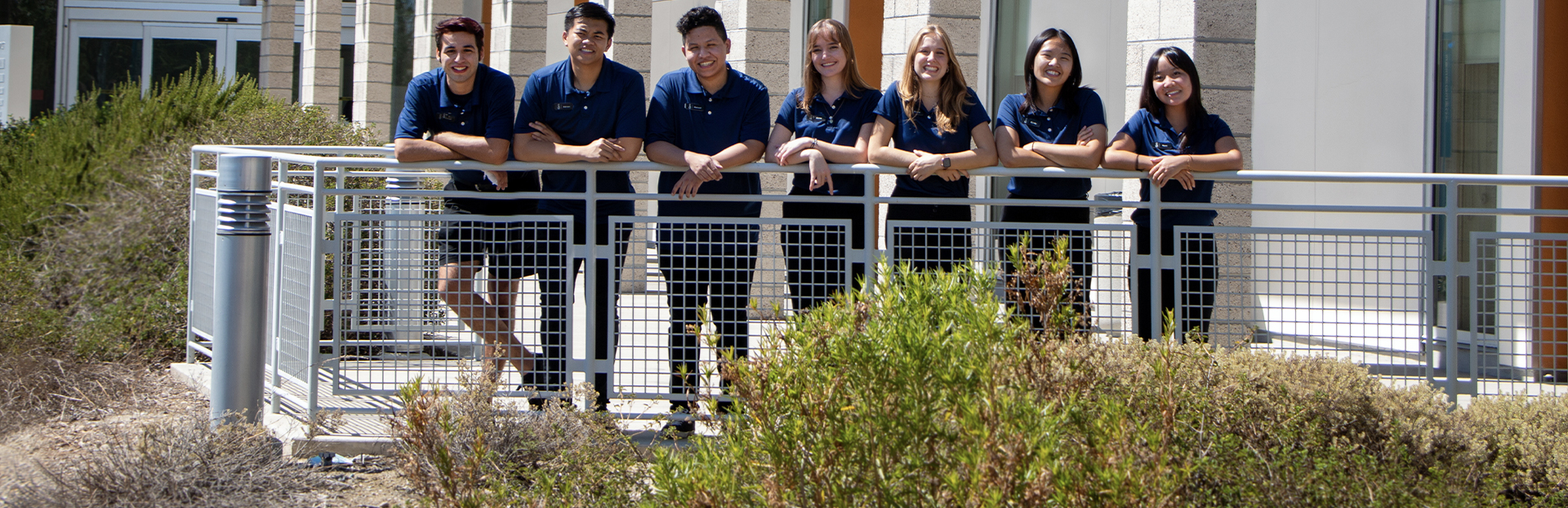 Students pose for a photo wearing matching navy blue polo shirts