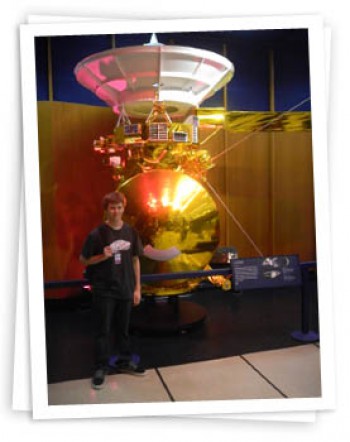 Alec poses in front of a scale model of the Cassini spacecraft