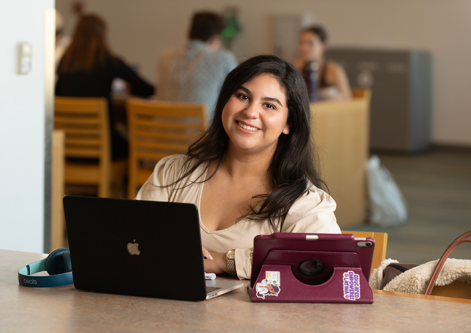 Alumna Anais Hernandez in the university library smiling while sitting at a table. 