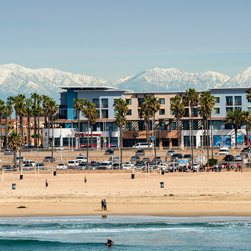 Snowy mountains behind pier at Huntington Beach