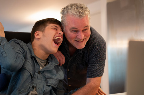 Father laughing with son in a wheelchair