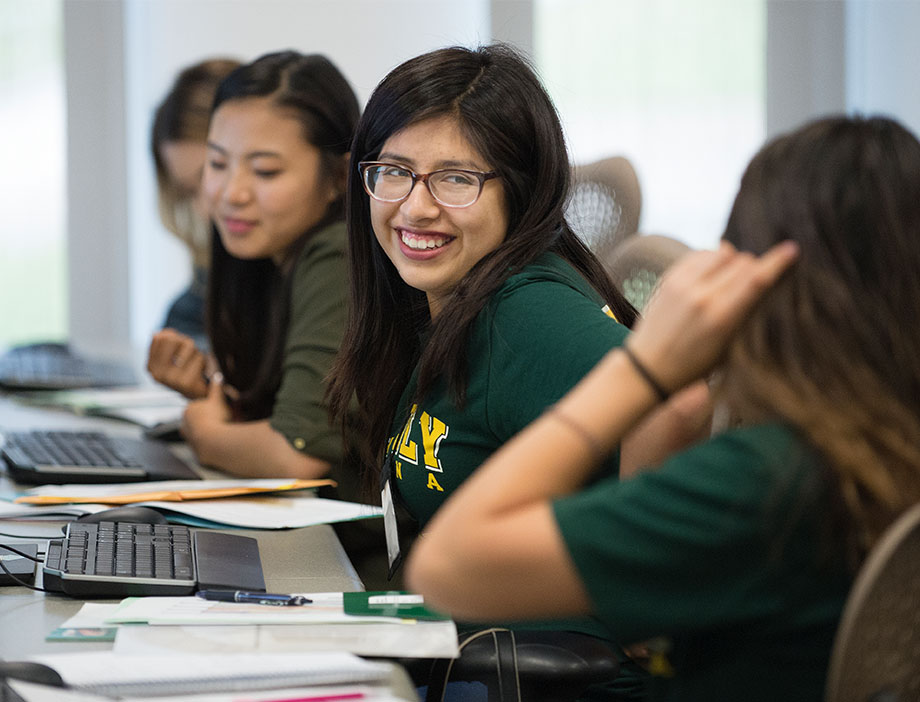 Student smiling at another student in a classroom