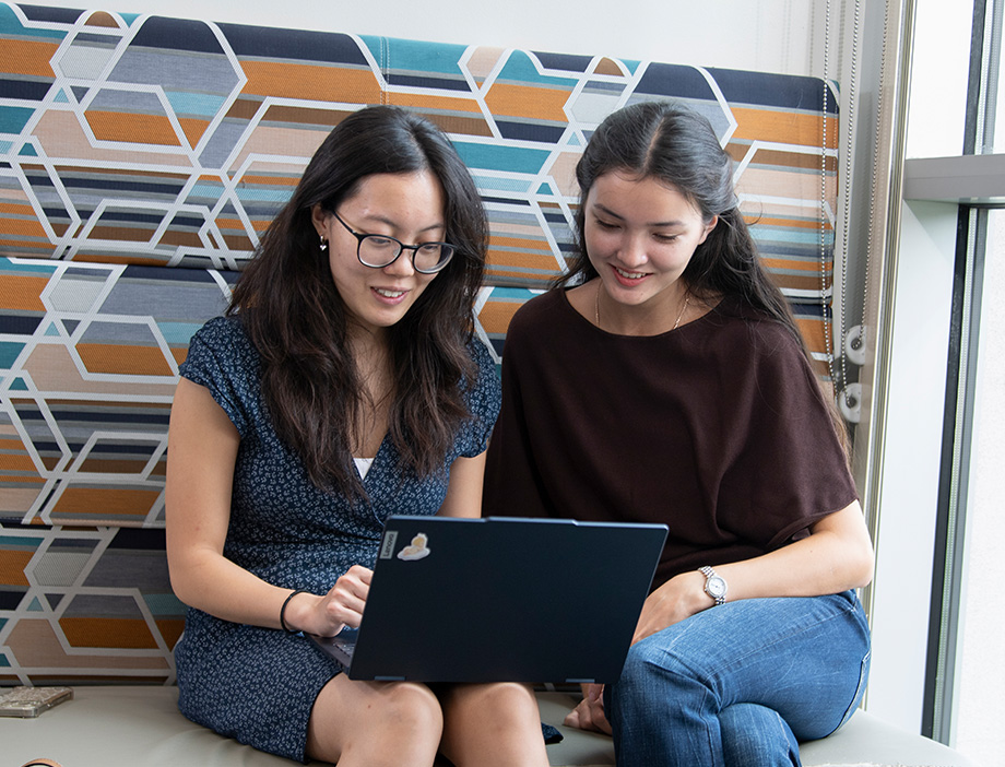 Two students looking at a laptop together and smiling