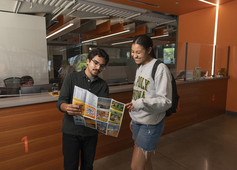 two students standing in a building reading a map