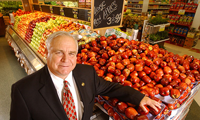Mike Provenzano poses by a display of apples in a market.