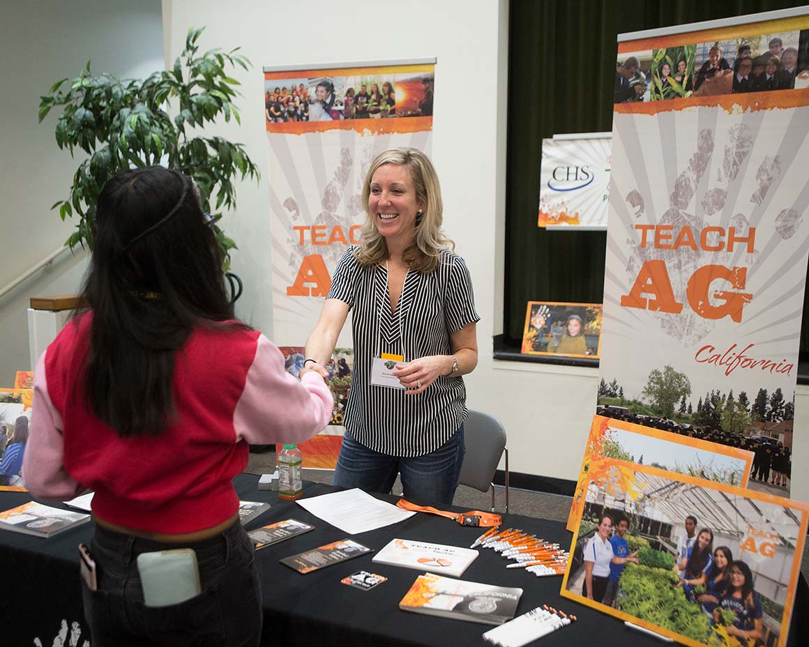 A Cal Poly Pomona student shakes hands with a representative for Teach Ag California at a career event.