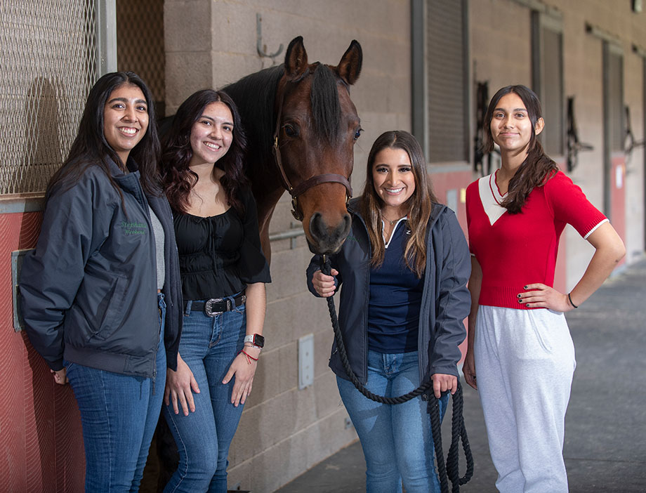 Four female students pose with a horse at the W.K. Kellogg Arabian Horse Center.
