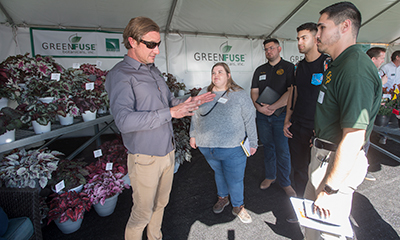 Cal Poly Pomona students listen to a horticultural industry representative at a flower sale.