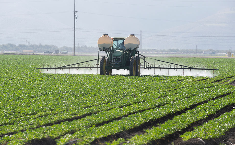 A tractor with tanks sprays a California farm field.