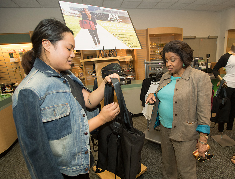 A student shows President Coley a handbag