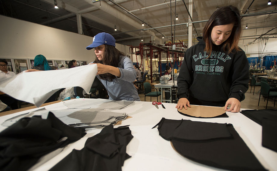 Students work on garments at a production table.