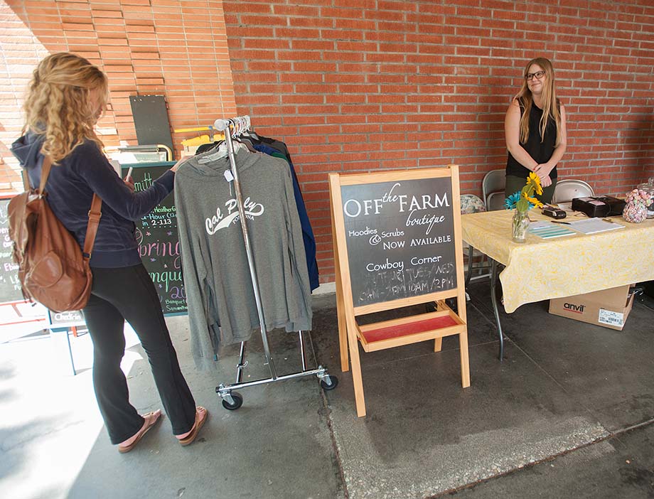 A customer peruses clothing items at a boutique as a student looks on.