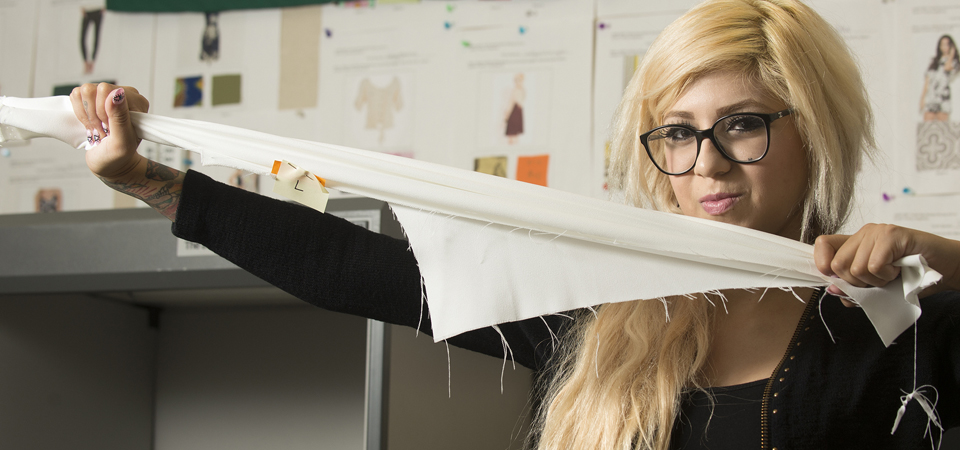 A student stretches a piece of fabric at the textile testing lab