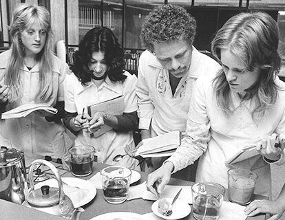 Three women and a man work in a kitchen lab during the 1970s.