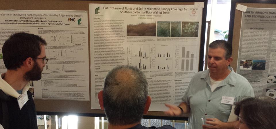 A researcher talks about his findings at a poster presentation.