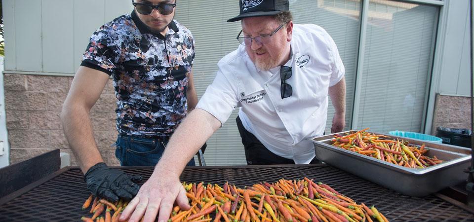 A chef and helper grill carrots