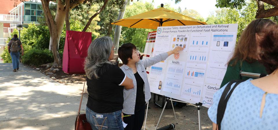 A student explains her poster presentation to a visitor.