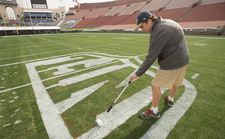 Student Sean McLaughlin paints the NFL logo on the LA Memorial Coliseum turf.