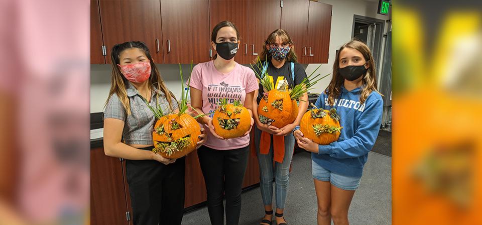 Four Make and Take class participants with their decorated pumpkins