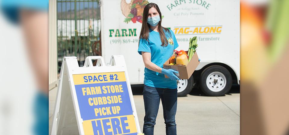 An employee waits to give a customer a box of groceries outside the Farm Store