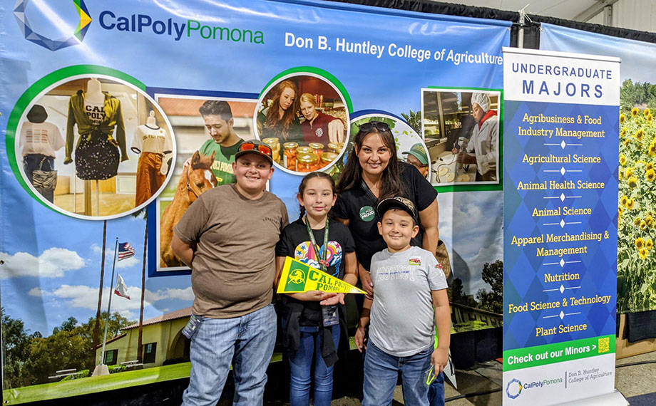 A alumna poses with her kids at a college display