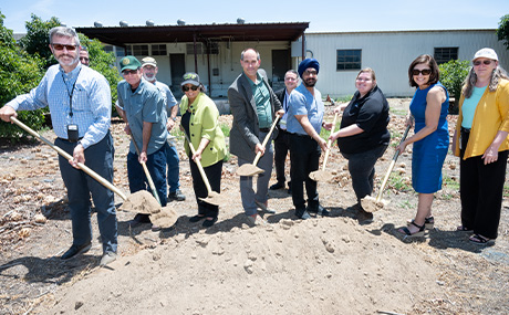 People with shovels pose for a photo at a groundbreaking ceremony.
