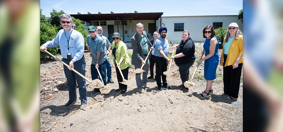 People with shovels pose for a photo at a groundbreaking ceremony.