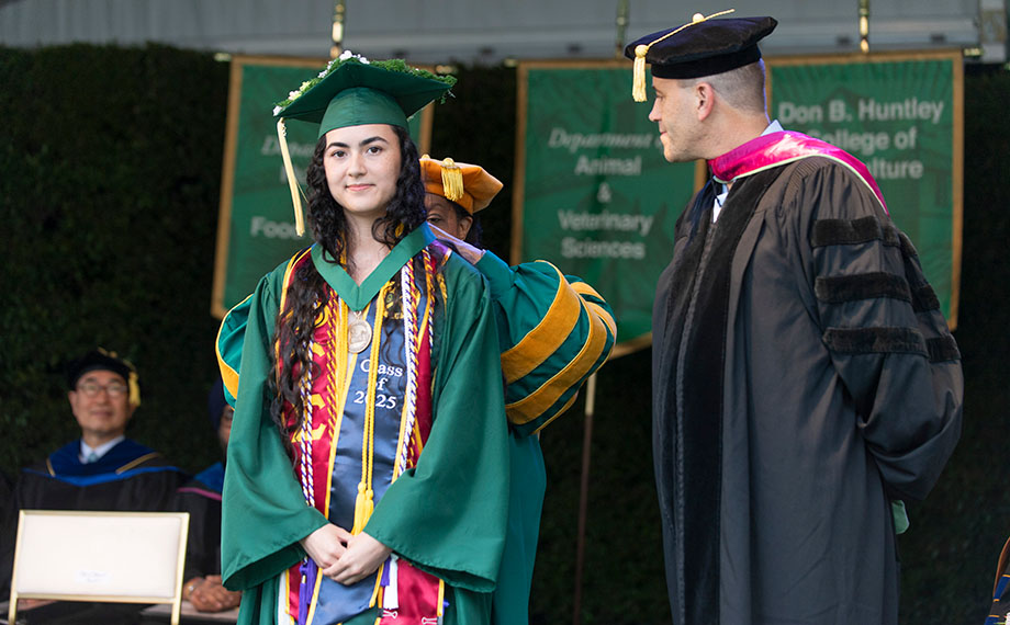 A woman drapes a medal around a student's neck.