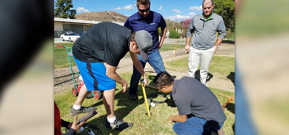 Students working on a turf research project while industry figures observe.
