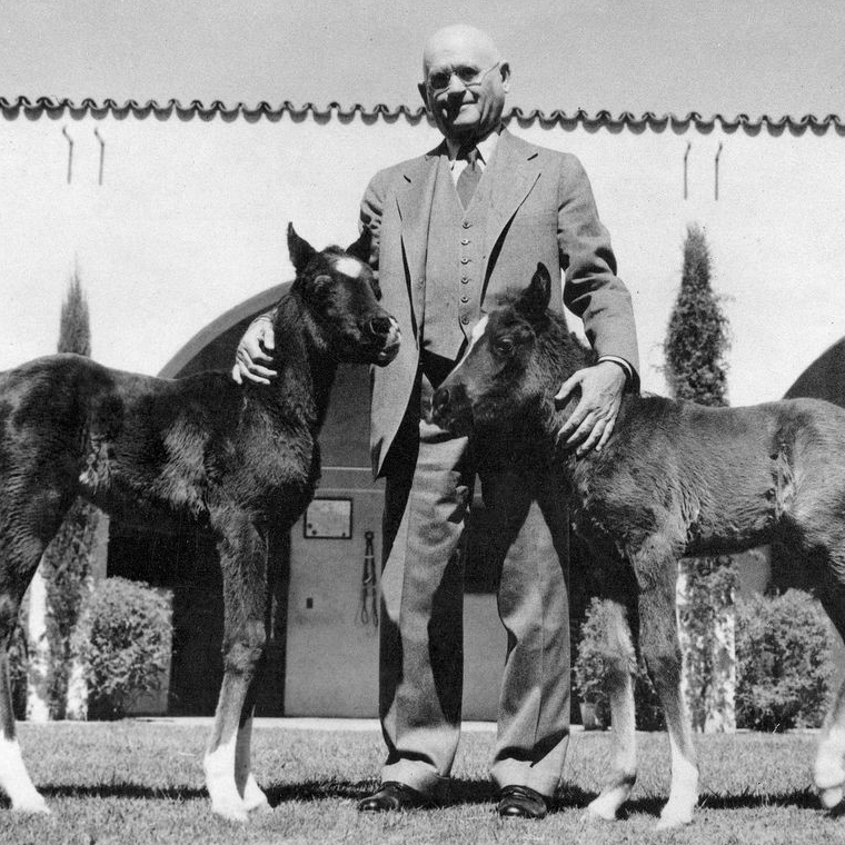 W. K. Kellogg standing with two foals
