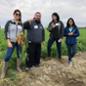 Students standing in a field holding freshly harvested carrots