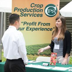 A woman speaks to a male student at the Crop Production Services table at Ag Career Day.