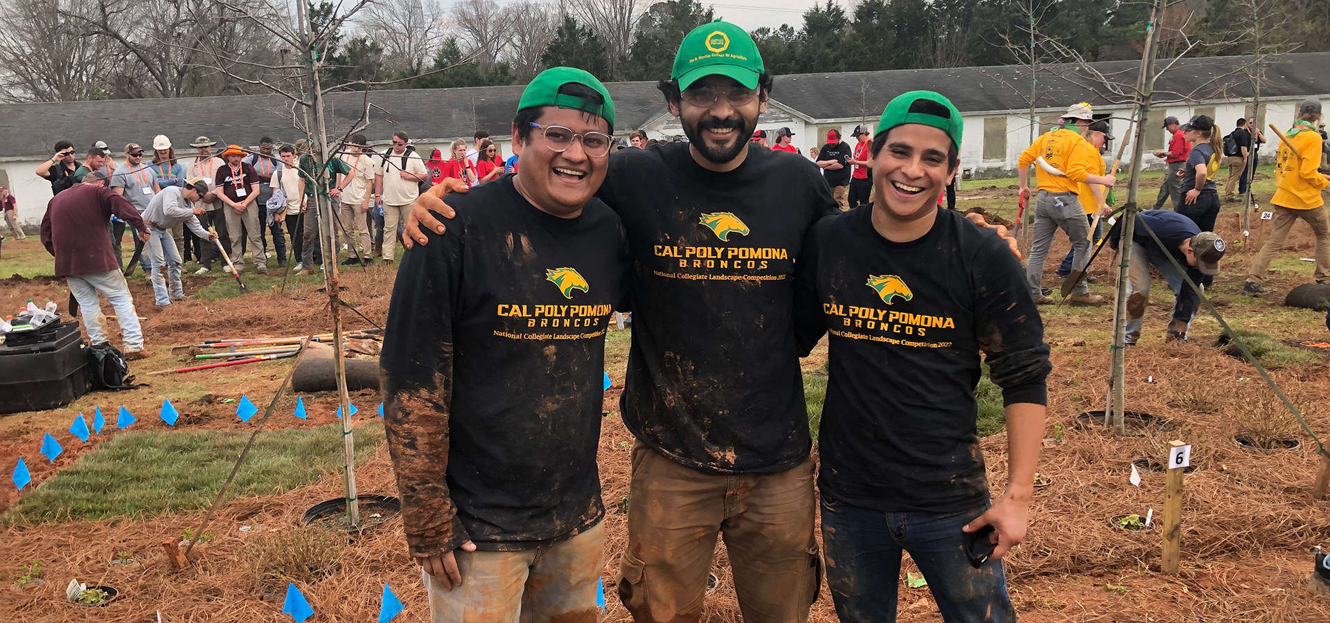 Three muddy, but happy, Cal Poly Pomona students outdoors at the competition.