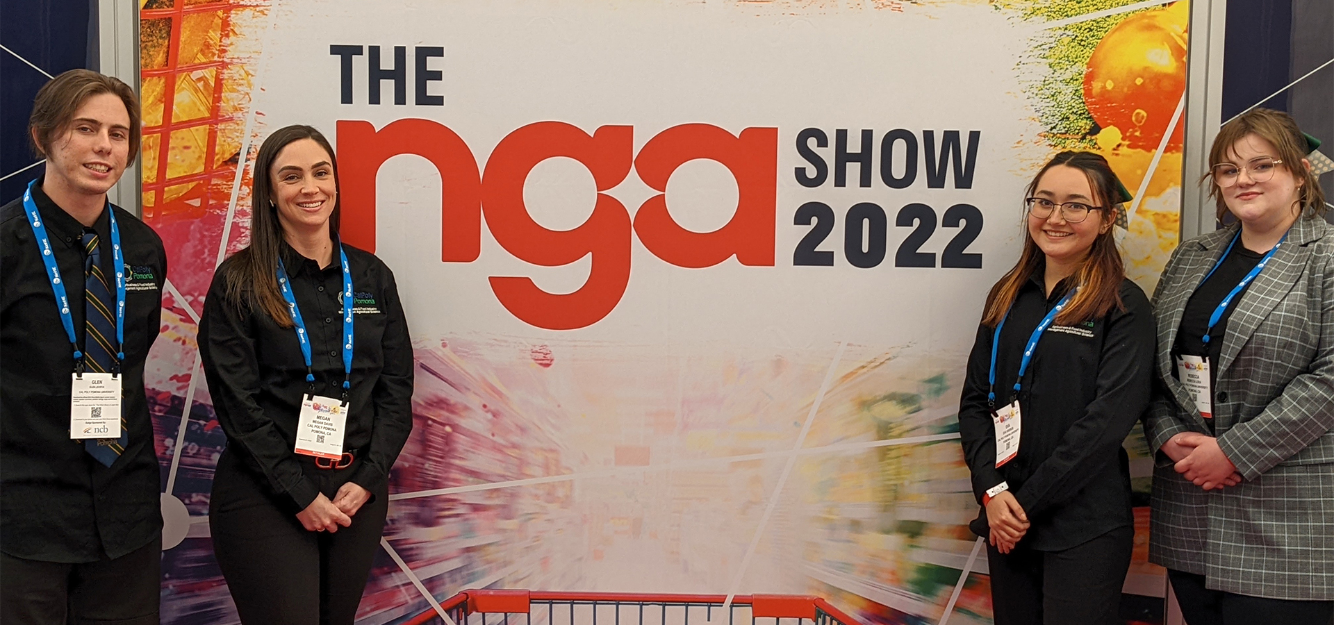 The four Cal Poly Pomona students pose in front of an NGA Show poster.