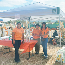 Advisor Tracey Takeuchi and two students pose at the booth