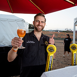 A man poses by holding up a glass of beer