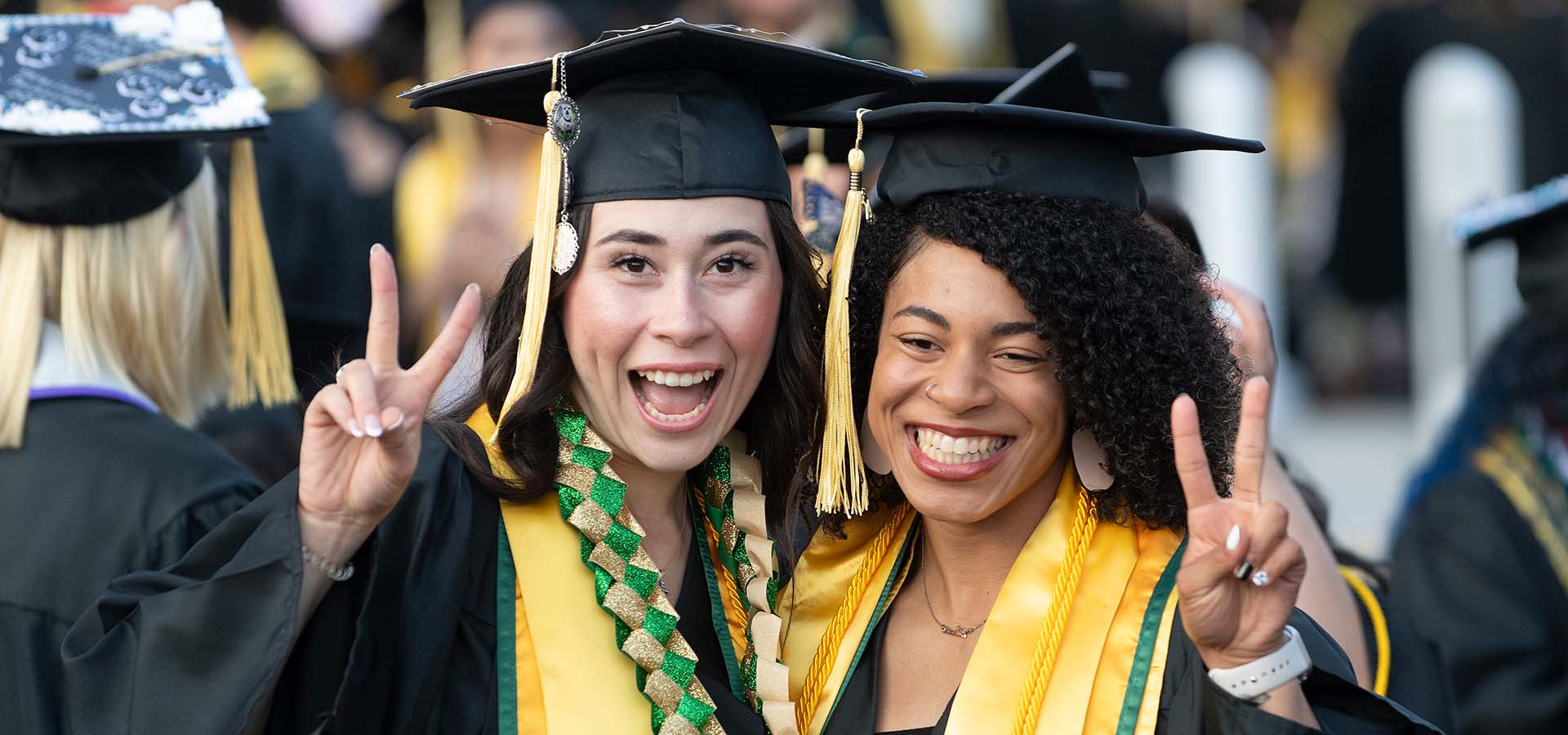 Two female students pose for the camera and make peace signs